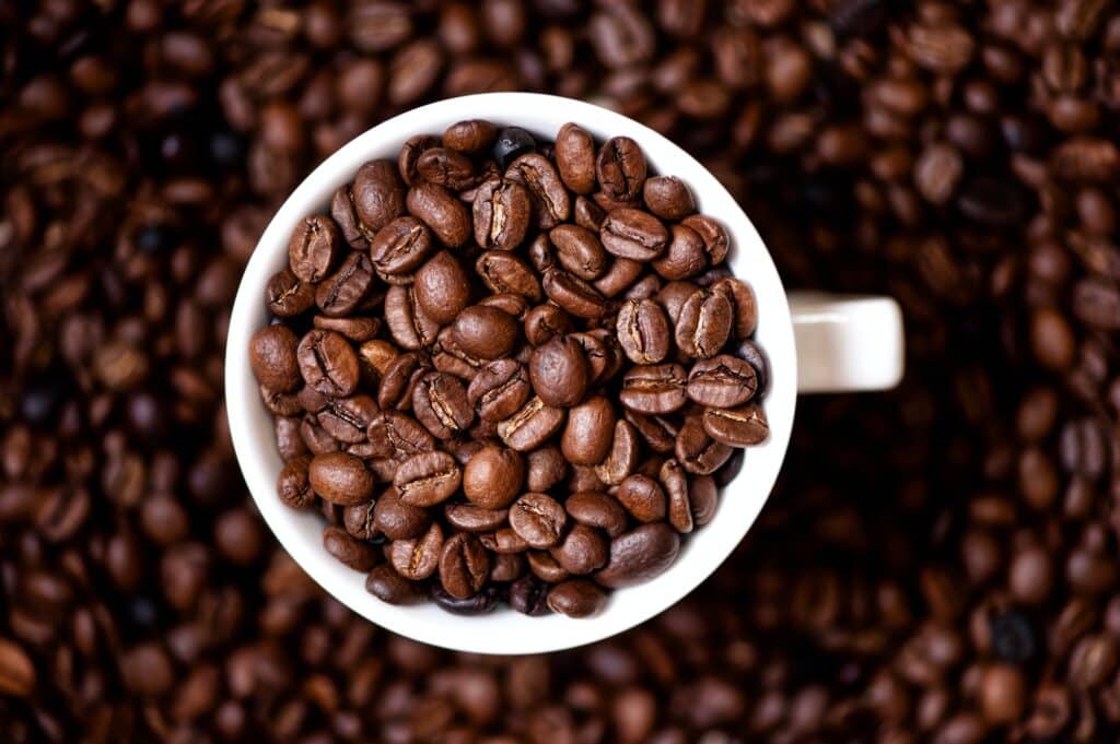 Coffee mug filled with coffee beans and coffee background