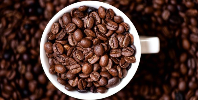 Coffee mug filled with coffee beans and coffee background