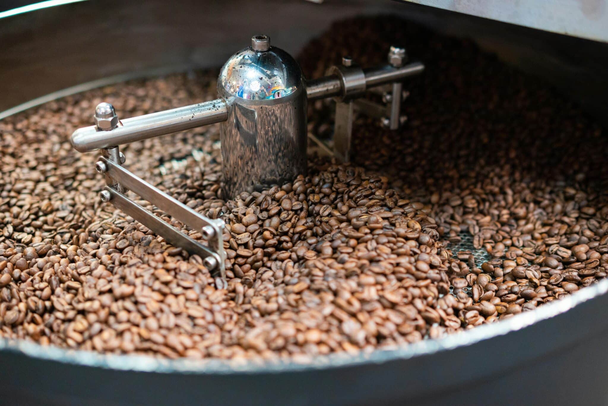 Kaffebønner i en professionel ristemaskine under risteprocessen, hvor varme og bevægelse udvikler smagsnuancerne.